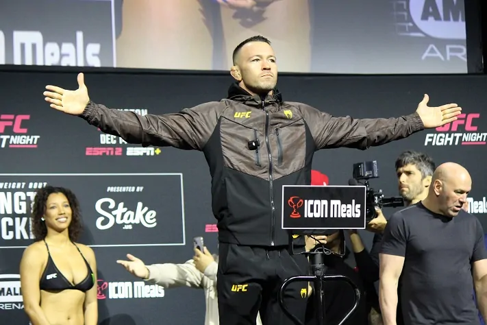 Colby Covington arms out at the UFC Tampa weigh-ins with Dana White behind him