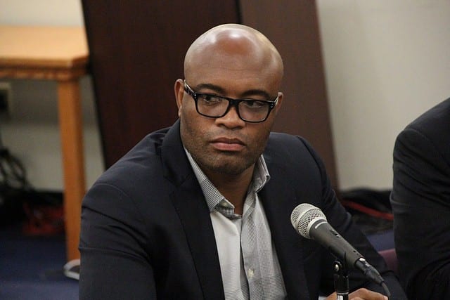 Anderson Silva in a suit and glasses speaks at a commission hearing