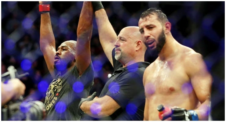 Jon Jones has his hand raised beside a dejected Dominick Reyes after UFC 247