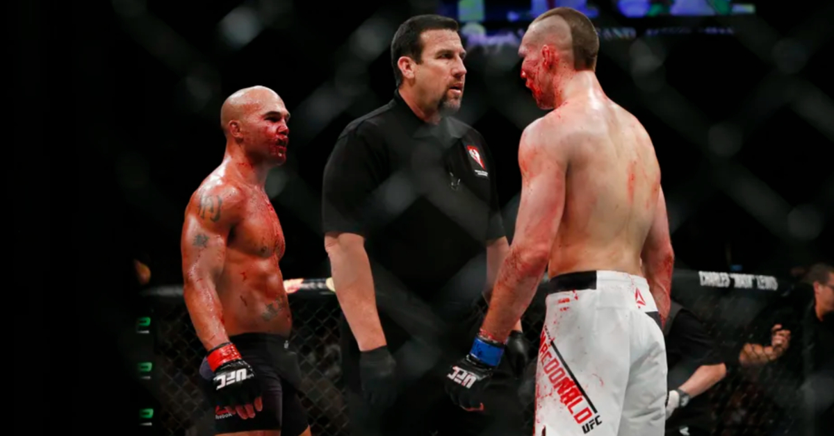 A bloodied Robbie Lawler and Rory MacDonald stare each other down between rounds at UFC 189