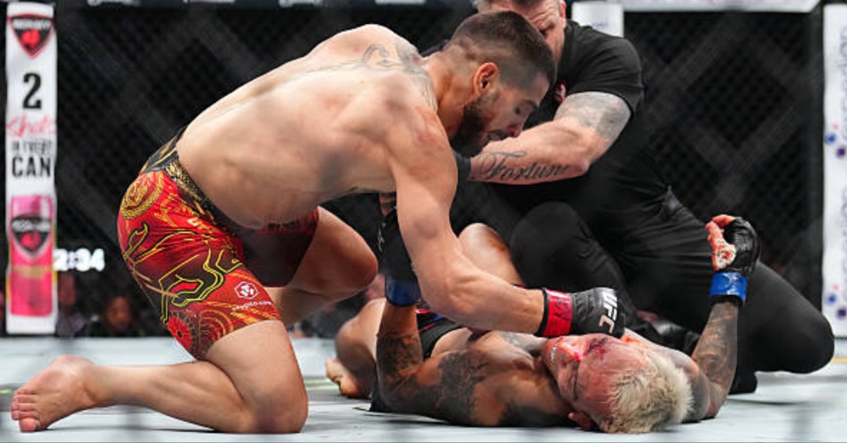 Ilia Topuria stands over Charles Oliveira after the knockout at UFC 317