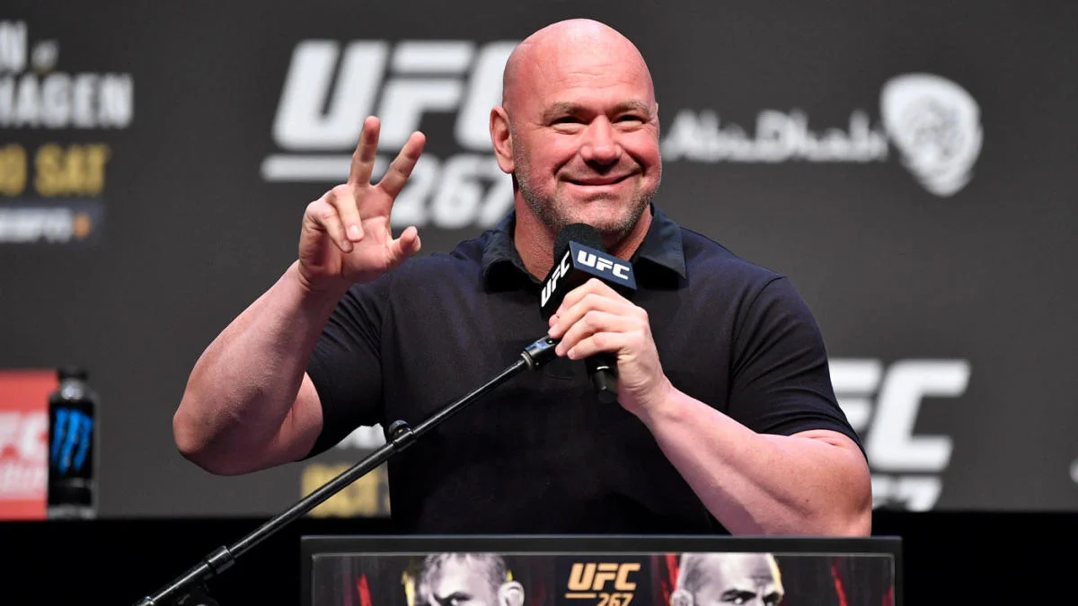 Dana White flashes a peace sign on stage at a UFC press conference
