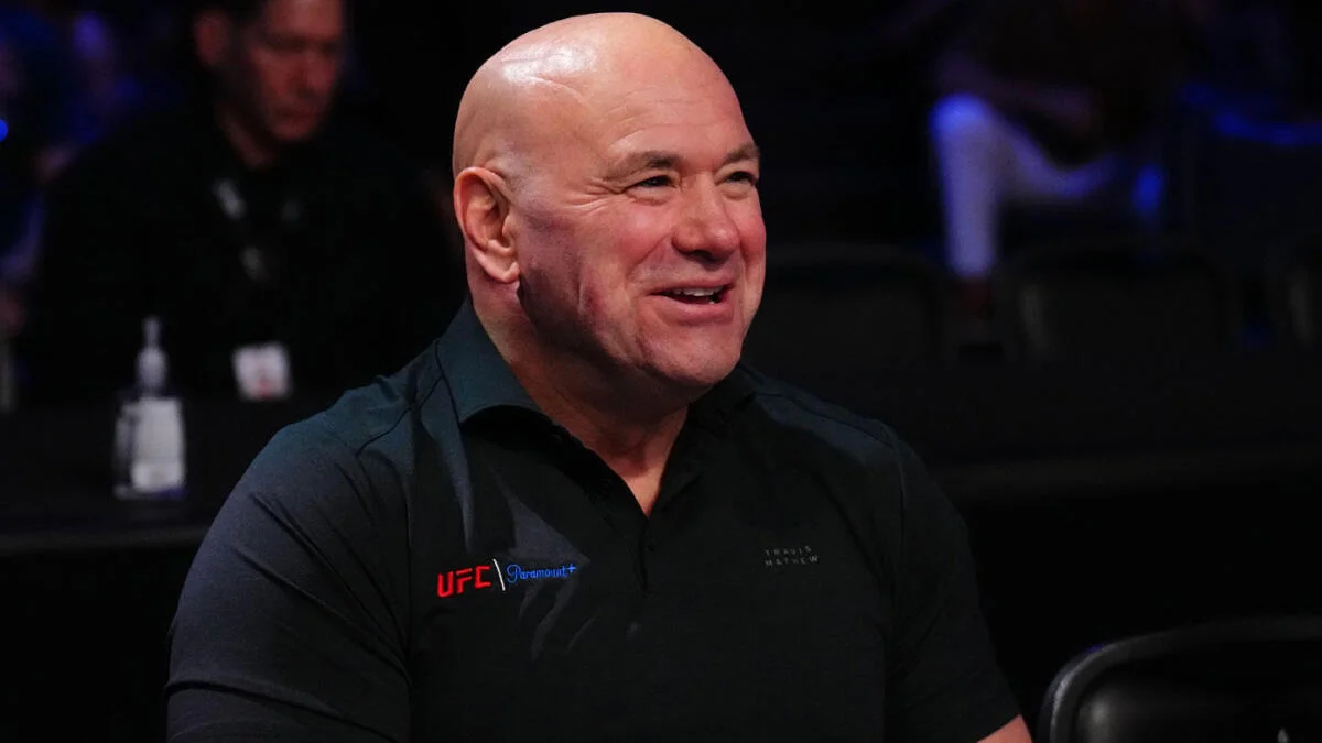 Dana White smiles cageside in a UFC and Paramount+ branded shirt