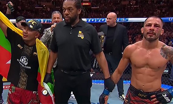 Joshua Van and Alexandre Pantoja wait for the decision with referee Herb Dean between them at UFC 331